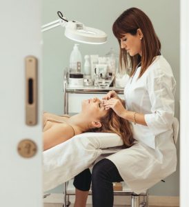Beautician performs facial treatment in salon, enhancing skincare and relaxation.