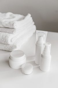 Elegant display of white skincare products and towels on a surface.
