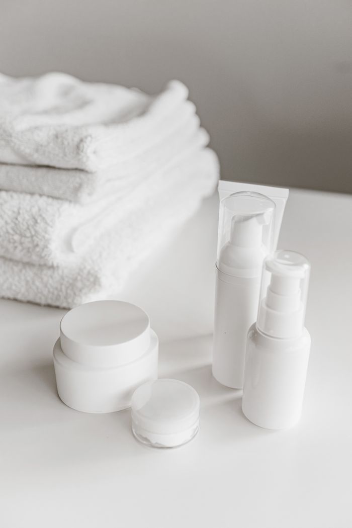 Elegant display of white skincare products and towels on a surface.